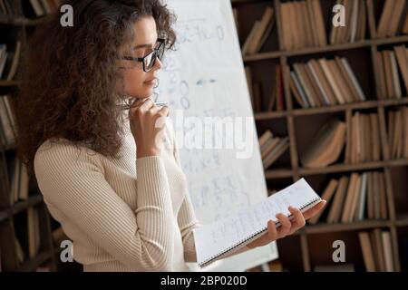 Junge lateinische Mathe Schullehrer trägt Brille halten Notebook im Klassenzimmer. Stockfoto