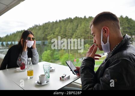 Paar im Restaurant tragen medizinische Schutzmaske Coronavirus Schutz soziale Distanzierung und Prävention Konzept männlich Rauchen und Überprüfung Stockfoto