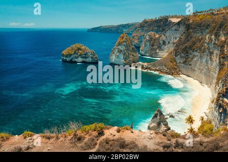 Der Reisende Mann steht auf dem Gipfel des Berges Blick auf das Meer und die Felsen. Reise- und Active Lifestyle Konzept. Abenteuer und Reise auf Bali, Indonesien. Stockfoto