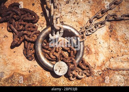 Rostiger Stahlring und Festmacherlinien in einem Seehafen. Rostige Eisenkette auf dem Boden. Stockfoto