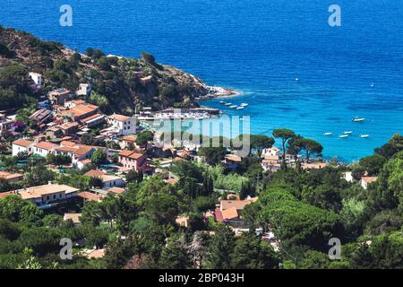 Küste mit Strand und kleinen Dorf auf der Insel Elba in Italien. Viele Leute am Strand sonnen. Blaues Meer mit Luftaufnahme. Haus Stockfoto
