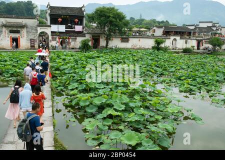 Eine steinerne Fußgängerbrücke überquert den Mondsee und führt Touristen in das Dorf Hongcun in der Stadt Huangshan. Stockfoto