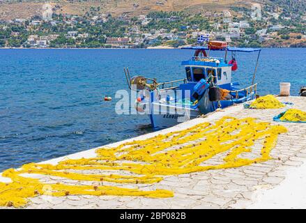 Fischerboot und gelbe Netze zum Trocknen auf dem Steg der kleinen Hafenstadt Telendos Island, Kalymnos, Dodekanes, Griechenland Stockfoto
