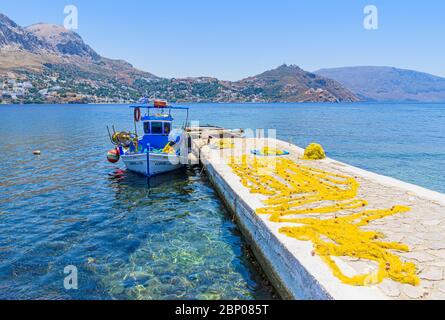 Fischerboot und gelbe Netze trocknen auf dem Steg der kleinen Hafenstadt Telendos Island, Kalymnos, Dodekanes, Griechenland Stockfoto