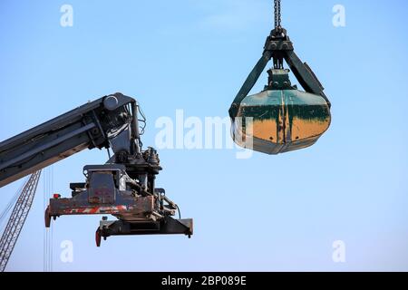 Großer Container-Handler und Clamshell-Bucket an einem lokalen Port. Stockfoto