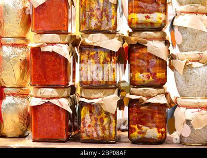 Viele Gläser mit süditalienischen Spezialitäten mit Sardellen, würzigen Paprika, Zwiebeln und Kirschtomaten in Öl Stockfoto