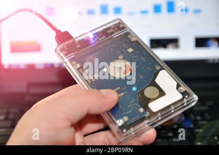 Eine externe oder tragbare Festplatte HDD, die an einen Laptop für die Datenübertragung oder Sicherung angeschlossen ist. Stockfoto