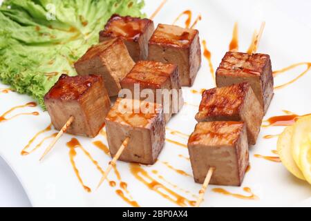 Gebratene Foie Gras Leber in Form von Kebabs auf Holzstäbchen mit Sauce und Zitrone. Stockfoto