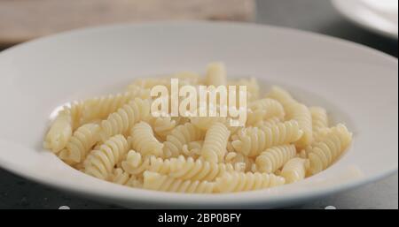 Dampf steigt aus gekochten heißen Fusilli in der weißen Platte Nahaufnahme Stockfoto