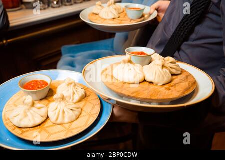 Saftige Khinkali auf einem weißen Teller. Serviert mit Sauce. Traditionelles Gericht. Stockfoto