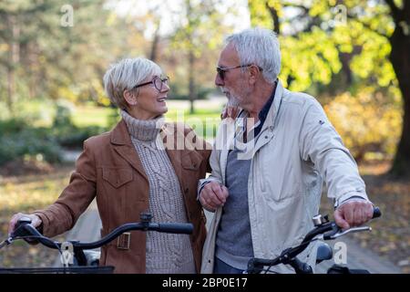 Altes Paar mit Fahrrädern, die im Park spazieren gehen Stockfoto