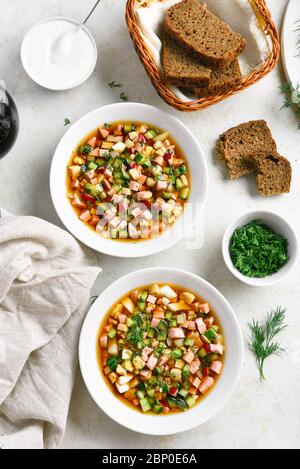 Traditionelle kalte russische Suppe Okroschka mit Wurst, Gemüse und Kvass über hellem Steinhintergrund. Draufsicht, flacher Lay Stockfoto