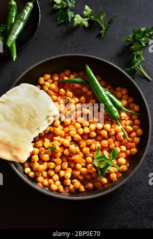 Knusprig geröstete Kichererbsen. Gericht im indischen Stil über schwarzem Stein Hintergrund. Vegetarisches veganes Food Konzept. Stockfoto