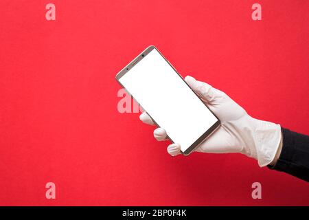 Hand in weißen Schutzhandschuh hält Smartphone mit leerem Bildschirm Stockfoto