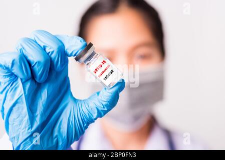 Asiatische Frau Arzt oder Krankenschwester in Uniform und Handschuhe tragen Gesichtsmaske Schutz im Labor hält Fläschchen Corona Impfstoff Flasche auf der Hand und bot Stockfoto