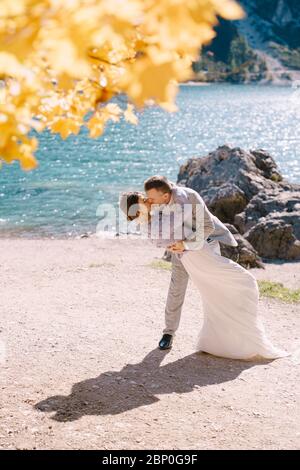 Braut und Bräutigam unter einem Herbstbaum, mit feurig gelbem Laub, am Lago di Prags in Italien. Hochzeitstag in Europa, am Pragsersee. Liebhaber Stockfoto