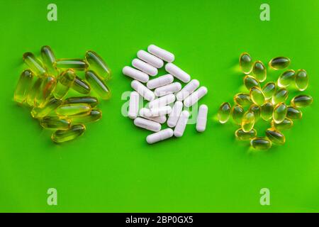 Gruppen von weißen Vitaminpräparaten mit Stapel von gelben Gelee-Pillen, Gesundheit diätetische Kapseln auf hellgrünem Hintergrund mit Kopieraum Stockfoto