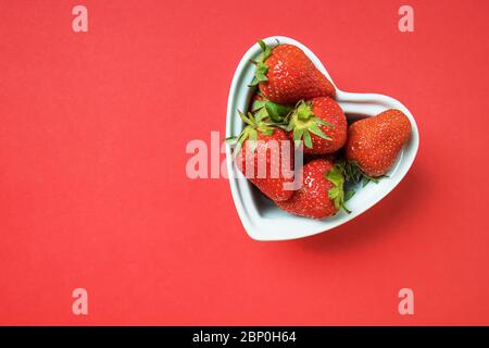 Frisch gepflückte Erdbeeren in Herz-Form-Schüssel Stockfoto