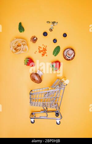 Verschiedene Lebensmittel rund um kleine Einkaufswagen Stockfoto