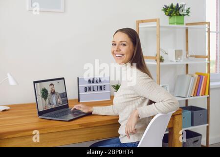 Online-Arbeit zu Hause. Eine Frau arbeitet an einem Tisch mit einem Laptop, sie spricht mit einem Partner über die Videoanruf-Chat-Anwendung zu Hause. Stockfoto