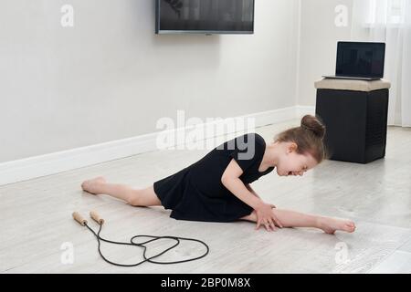 Kleines Mädchen tun Split und Gymnastik Übung zu Hause Gefühl viel Schmerz Stockfoto