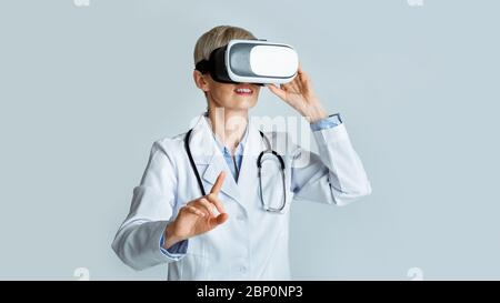 Virtuelle Schulungen für Mediziner. Frau Arzt in Virtual Reality Brille zeigt Finger Stockfoto