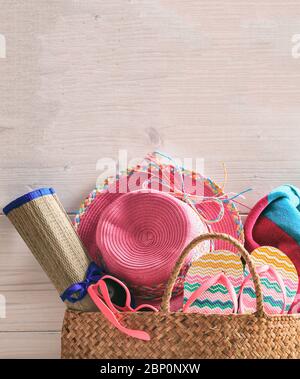 Sommer Strandtasche und Accessoires auf rosa Holzhintergrund. Strohhut, Flip Flops, Sonnenbrille und Handtuch. Vertikales Foto, Kopierbereich. Stockfoto