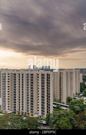 Dramatische Wolken gegen blauen Himmel mit modernen Wohngebäuden und urbaner Landschaft im Vordergrund. Blick vom Fenster während des Lasttrenners SG Stockfoto