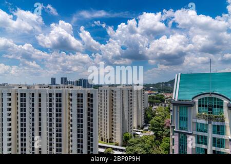 Dramatische Wolken gegen blauen Himmel mit modernen Wohngebäuden und urbaner Landschaft im Vordergrund. Blick vom Fenster während des Lasttrenners SG Stockfoto