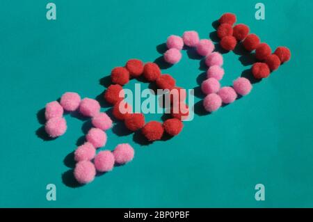 Festliche leuchtend rosa und rote Pom Poms als Symbol des neuen Jahres 2021 auf dem dunklen mintfarbenen Hintergrund. Weiche flauschige Zahlen bilden Textil an der Diagonale Stockfoto