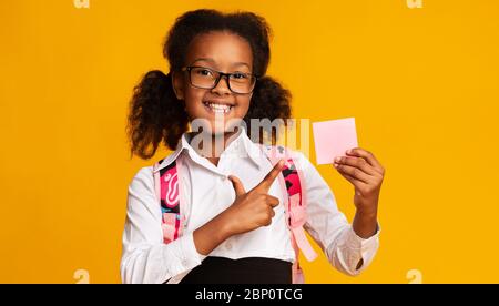 Schulmädchen, Zeigt Finger Auf Leere Papierkarte, Studioaufnahme Stockfoto