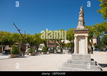 Sonniger Dorfplatz in Rasteau mit Kriegsdenkmal und bestäuberten Platanen, die Schatten spenden Stockfoto