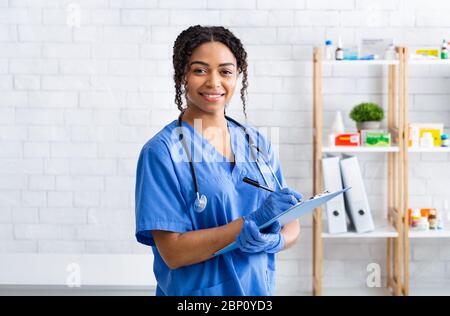 Lächelnd afroamerikanischen Tierarzt doc mit Clipboard in Klinik, Porträt Stockfoto