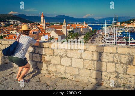 Hübsche Frau, die ein Foto mit dem Telefon aus dem Schloss. Glückliche Reisende Frau mit Smartphone, die Reise Bilder in Trogir Altstadt aus dem Turm Stockfoto