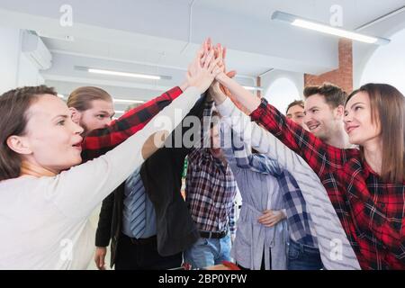 Geschäftsleute in lässiger Kleidung geben hohe fünf im Büro Stockfoto