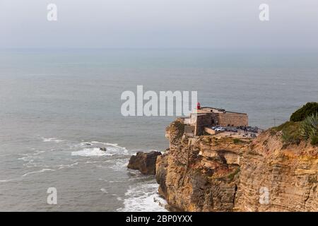 NAZARE, PORTUGAL - 25. FEBRUAR 2017: Die Menschen beobachten die Wellen vom Erzengel St. Michael Fort am Praia do Norte in Nazare, Portugal Stockfoto