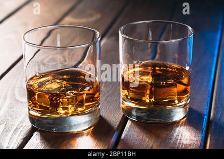 Gläser mit Whiskey oder anderem Alkohol auf einem Holztisch aus der Nähe. Stockfoto