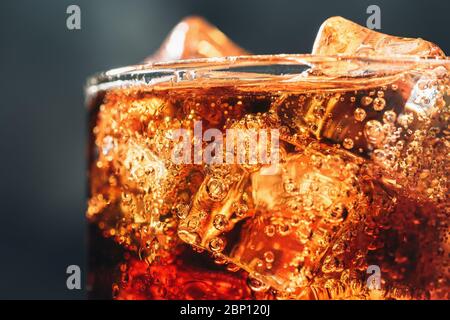 Glas mit Eiswürfeln und Blasen von frischen kohlensäurehaltigen Cola Soda Drink, Makro-Foto aus nächster Nähe. Stockfoto