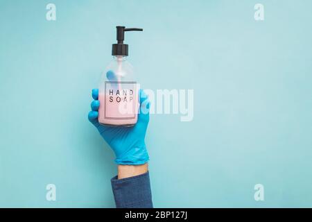 Erhobene Hand, die eine Flasche Handseife hält Stockfoto