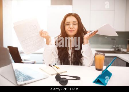 Eine schöne junge Frau arbeitet in der Küche in ihrem Haus, sie ist sehr müde. Aber immer noch viel Arbeit. Zu Hause zu arbeiten ist schwierig und ermüdend. Stockfoto