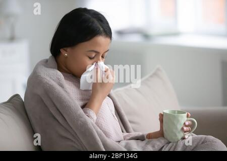 Afrikanische Frau in Plaid gewickelt, Schlag Nase trinkt kalte Medizin Stockfoto