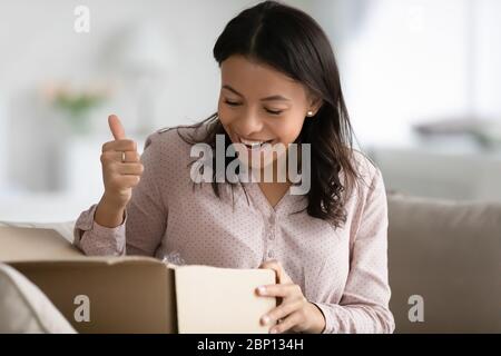 African Frau öffnet Paketkasten fühlt sich von gelieferten Waren zufrieden Stockfoto