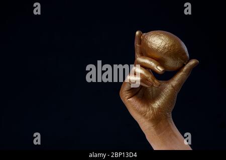 Kreatives Konzept mit Obst. Goldene Zitrone in der Hand Stockfoto