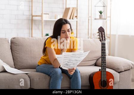 Nachdenkliche Latein Mädchen studieren Noten, lernen, Gitarre zu Hause spielen Stockfoto