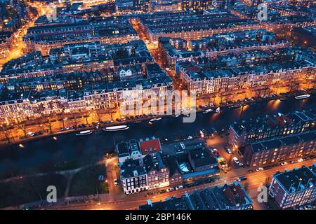 Amsterdam Niederlande Luftaufnahme bei Nacht. Alte Tanzhäuser, Fluss Amstel, Kanäle mit Brücken, alte europäische Stadtlandschaft von oben. Stockfoto