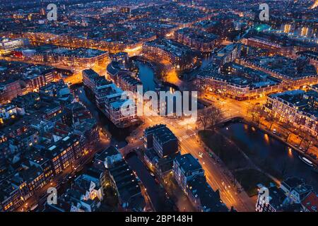 Amsterdam Niederlande Luftaufnahme bei Nacht. Alte Tanzhäuser, Fluss Amstel, Kanäle mit Brücken, alte europäische Stadtlandschaft von oben. Stockfoto