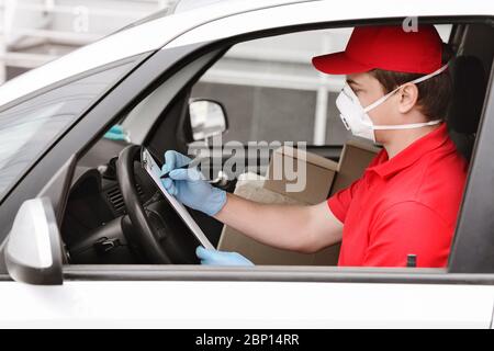 Schnelle Lieferung mit Kurier zu Hause. Mann im Auto prüft Daten in Boxen Stockfoto