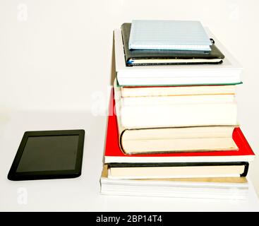Stapel von Textbüchern und Büchern neben einem E-Book auf weißem Hintergrund Stockfoto