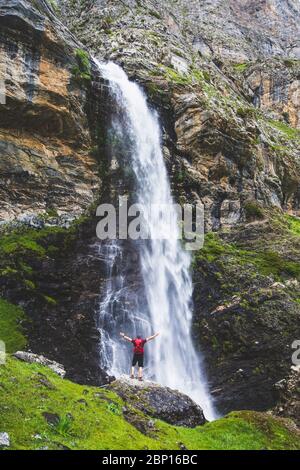 Mann unter einem spektakulären Wasserfall in den Bergen Stockfoto