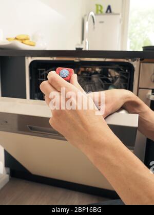 Ein Mann mittleren Alters stattet einen Geschirrspüler mit einem Reinigungslasche, Reinigungskonzept aus Stockfoto